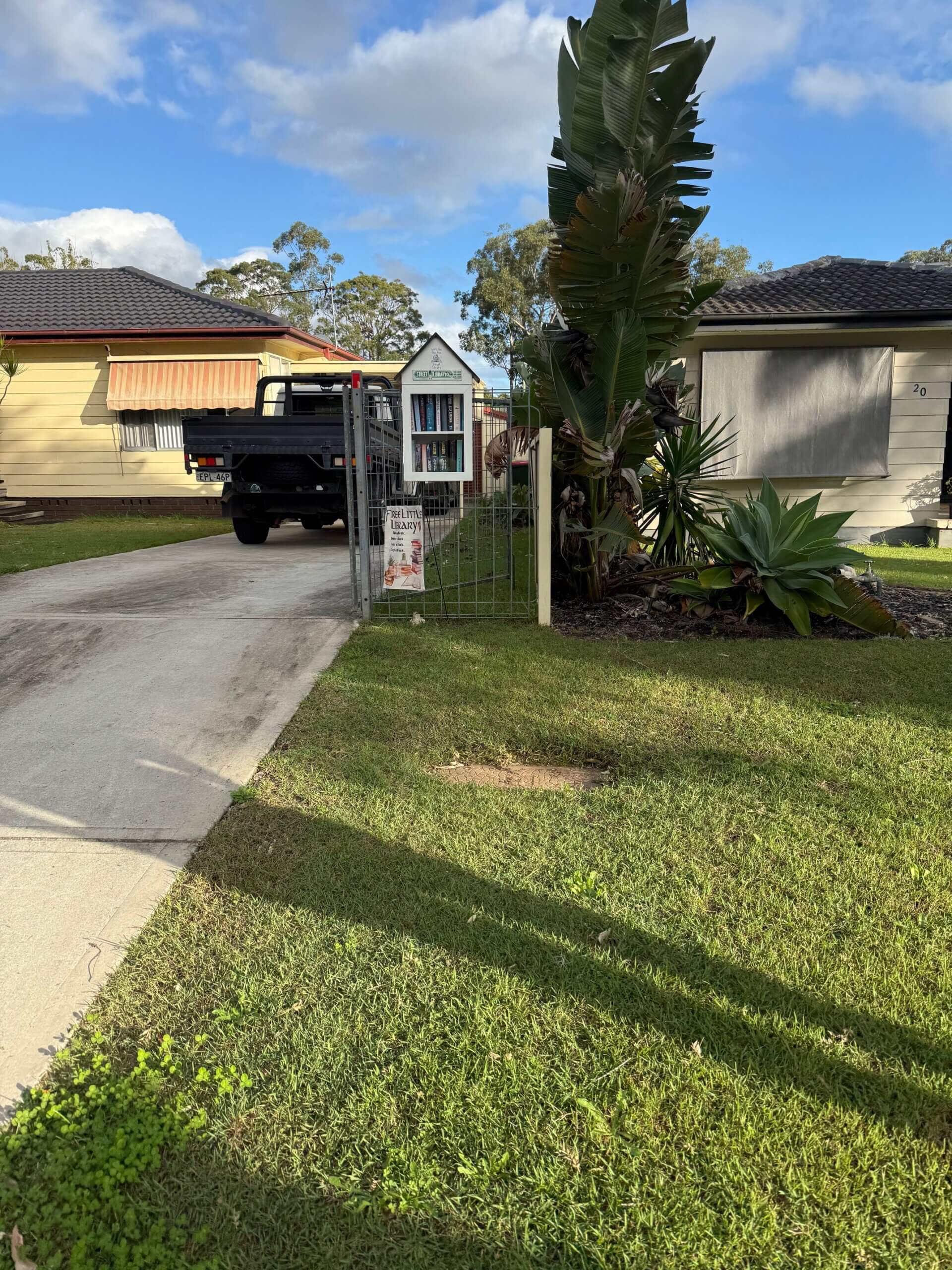 A street library up a driveway on a fence.