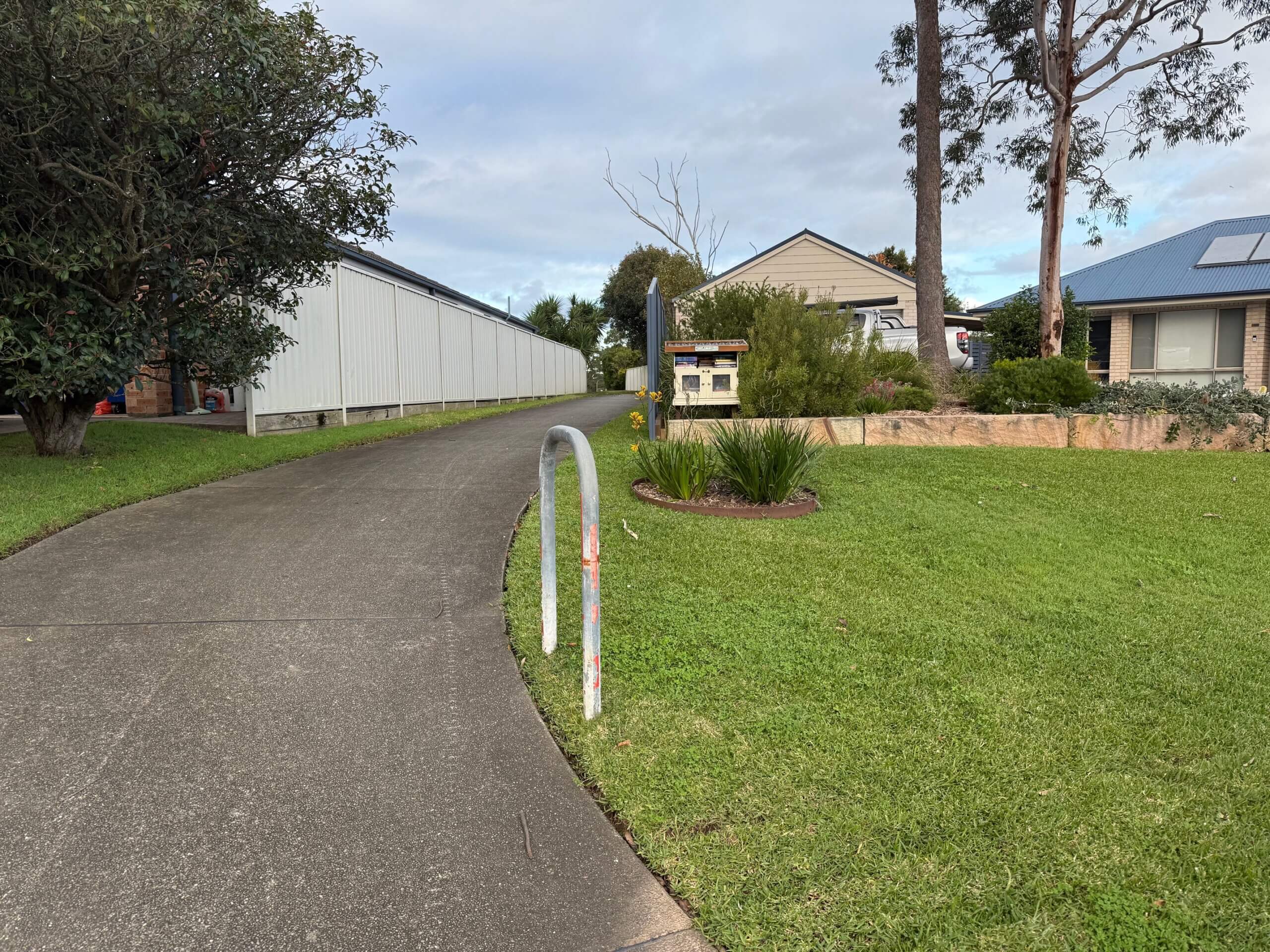 A street library up a driveway on a fence.